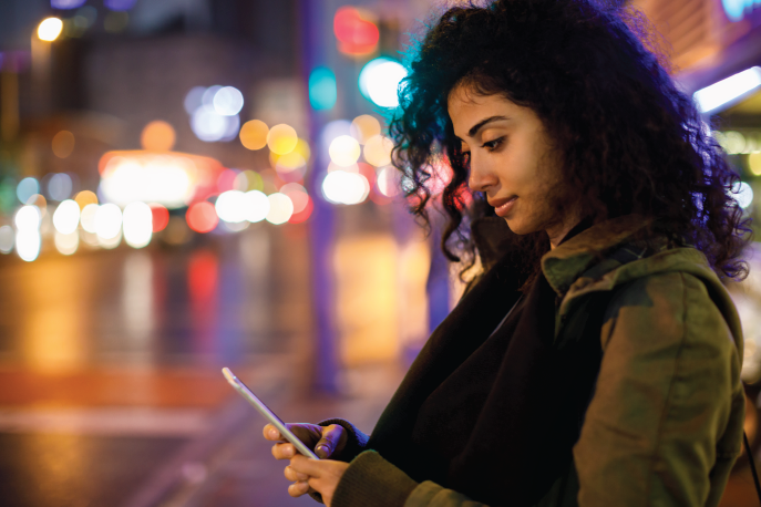 Woman standing on the sidewalk looking at her phone