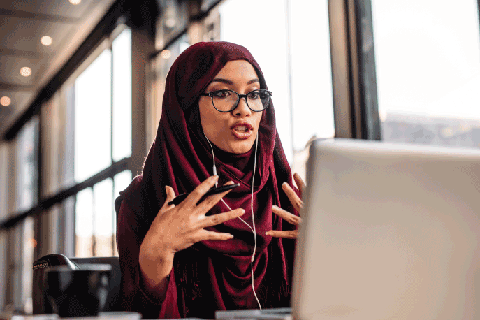 Woman wearing a hijab and glasses having a video chat conversation