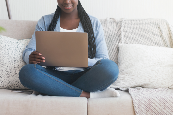 Black woman sitting on a couch using a laptop