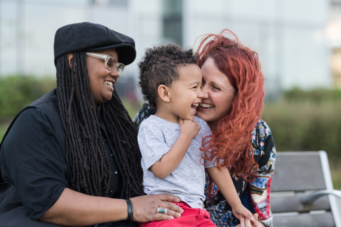 Two women holding and laughing with their child