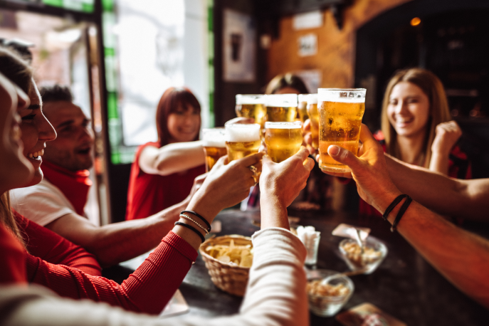 Group of people in a bar holding up their glasses to "cheers"