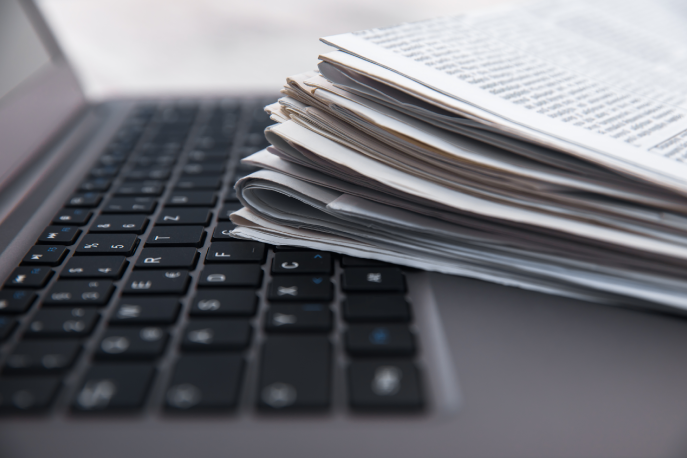 Stack of newspapers on an open laptop