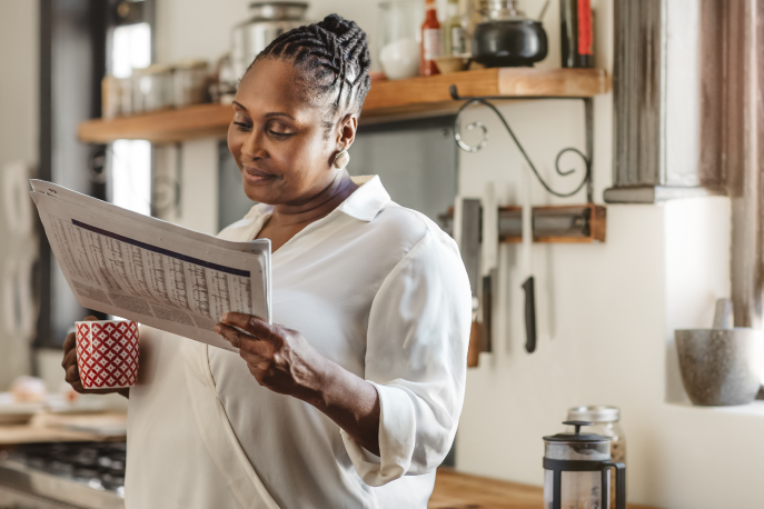 Black woman reading newspaper in kitchen