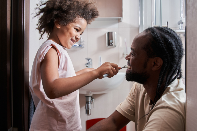 Daughter brushing father's teeth