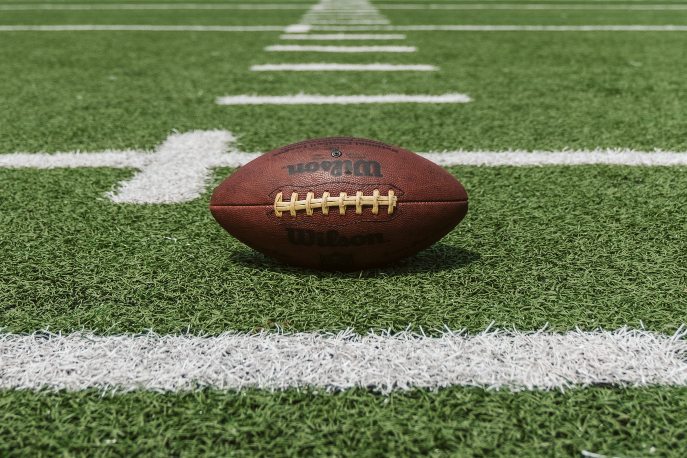 Football resting on grassy field during daytime.