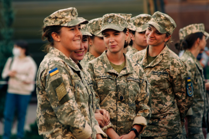 Three women in military uniform smiling and talking too one another