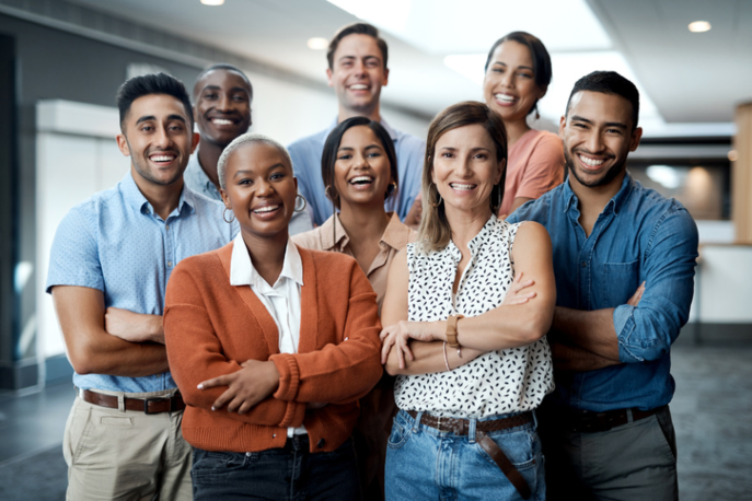 Group of racially diverse young adults in workplace smiling at camera.
