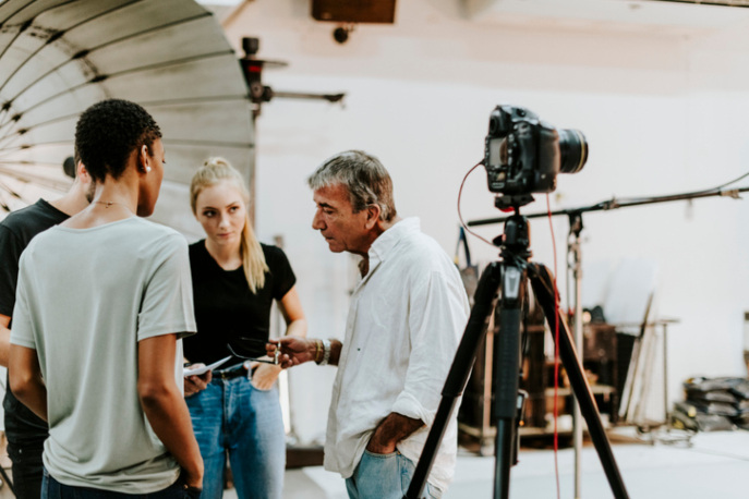 A film set with a white male director speaking with 2 Black and white actresses.