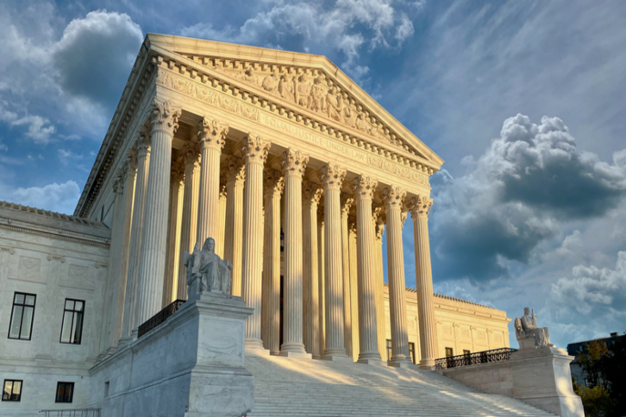 The Supreme Court building lit by the sunrise.