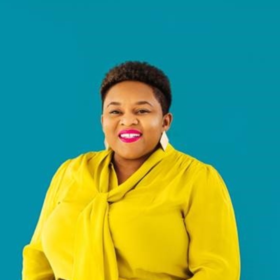 Black woman with short hair and a yellow blouse on a teal background.