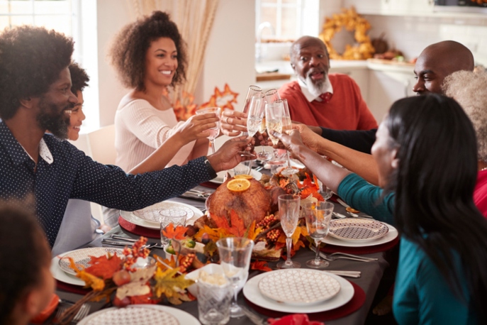 Black family toasting glasses around a Thanksgiving table.