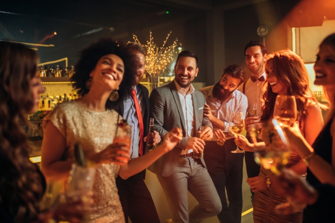 Colleagues in cocktail wear on a rooftop, fireworks behind them.