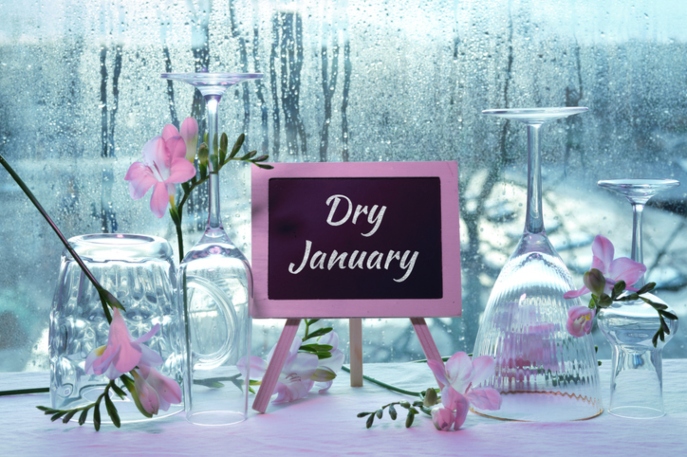 Empty glasses, upside down, next to a pink sign that says "Dry January"