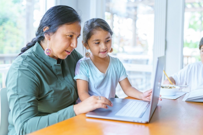 Native American mom and daughter in front of a computer.