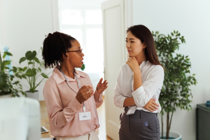 Asian woman colleague listening to Black woman colleague.