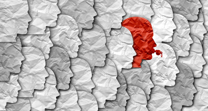 Crumbled paper silhouettes of heads, one of them red blowing a whistle