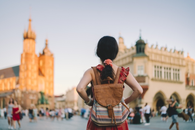 Back of woman with a backpack looking at a European street.
